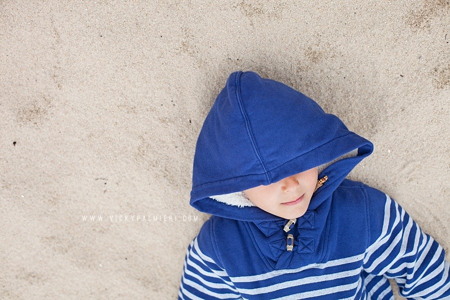 Shooting With Soul 52 Project - Week 2 - Cold Theme Boy lying down on sand wearing a blue hoodie covering his eyes.